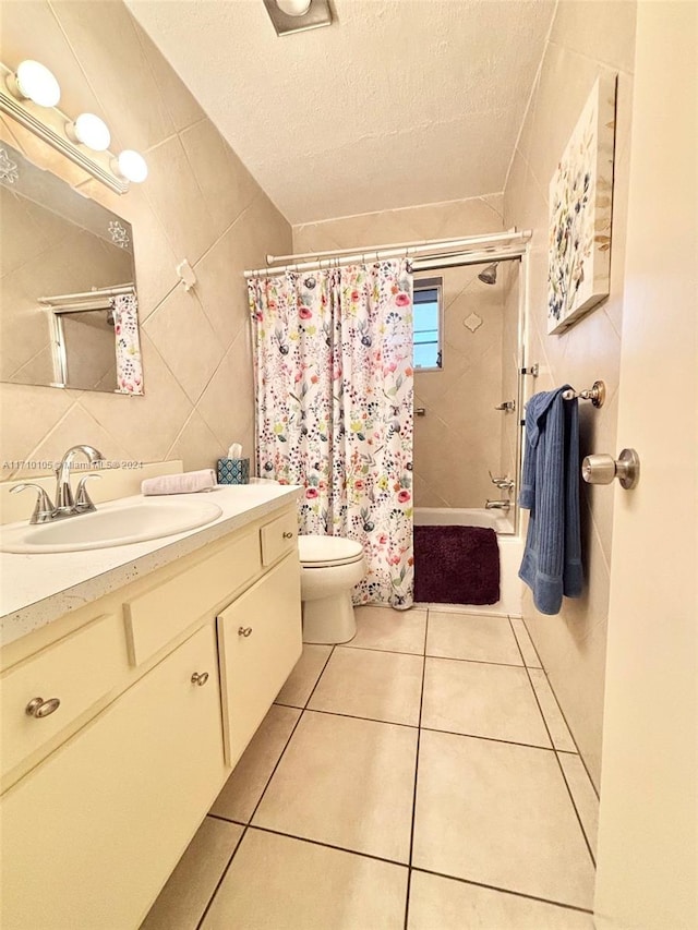 full bathroom featuring vanity, a textured ceiling, shower / bathtub combination with curtain, tile walls, and tile patterned flooring