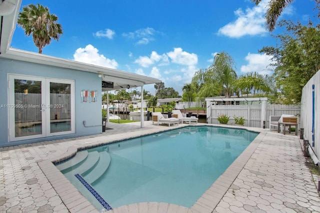 view of swimming pool with a patio area, french doors, and a water view