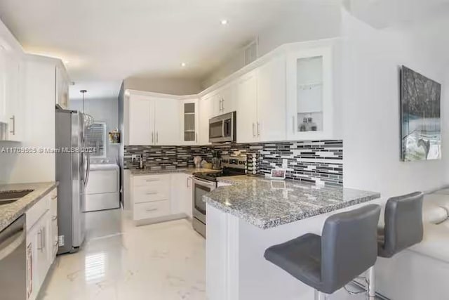 kitchen featuring a kitchen bar, appliances with stainless steel finishes, tasteful backsplash, and white cabinetry