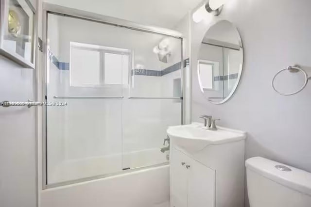 full bathroom featuring vanity, toilet, and shower / bath combination with glass door