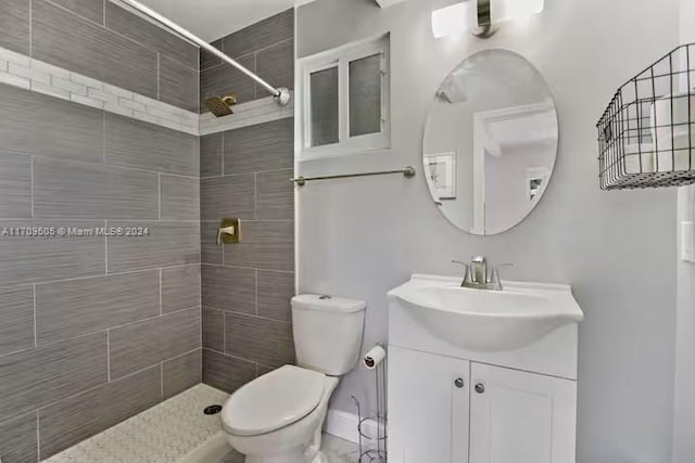 bathroom with a tile shower, vanity, and toilet