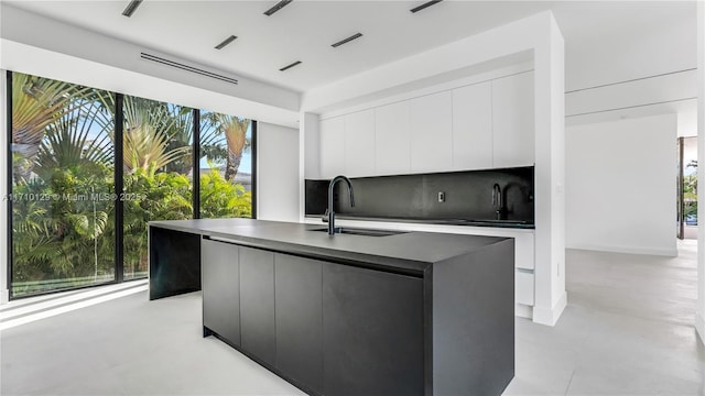 kitchen with white cabinets, sink, and an island with sink