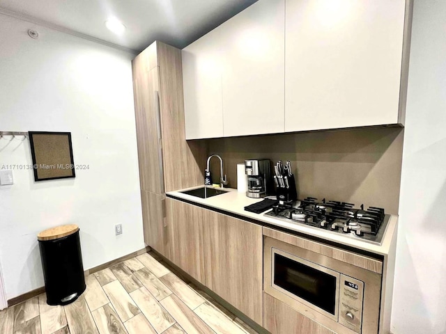 kitchen featuring light brown cabinets, sink, stainless steel appliances, light hardwood / wood-style flooring, and white cabinets