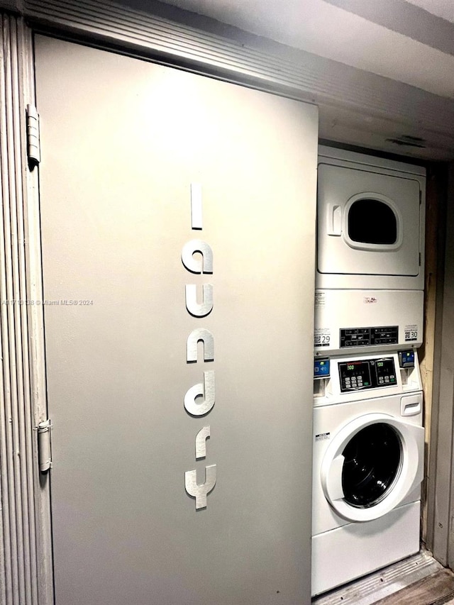 laundry area featuring wood-type flooring and stacked washer and clothes dryer