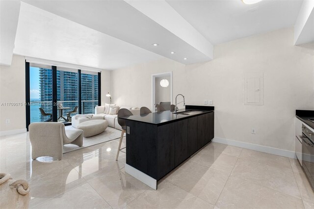 kitchen featuring a wall of windows, kitchen peninsula, sink, and a kitchen bar