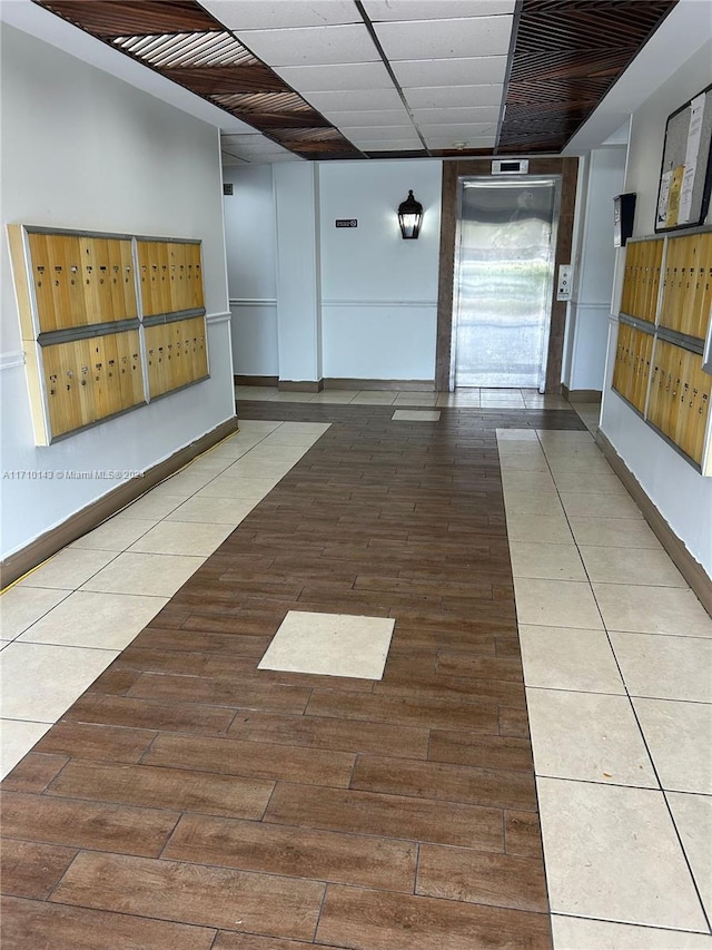 corridor with tile patterned floors, a mail area, and elevator