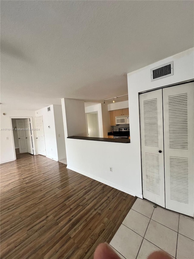 unfurnished living room with hardwood / wood-style flooring and a textured ceiling