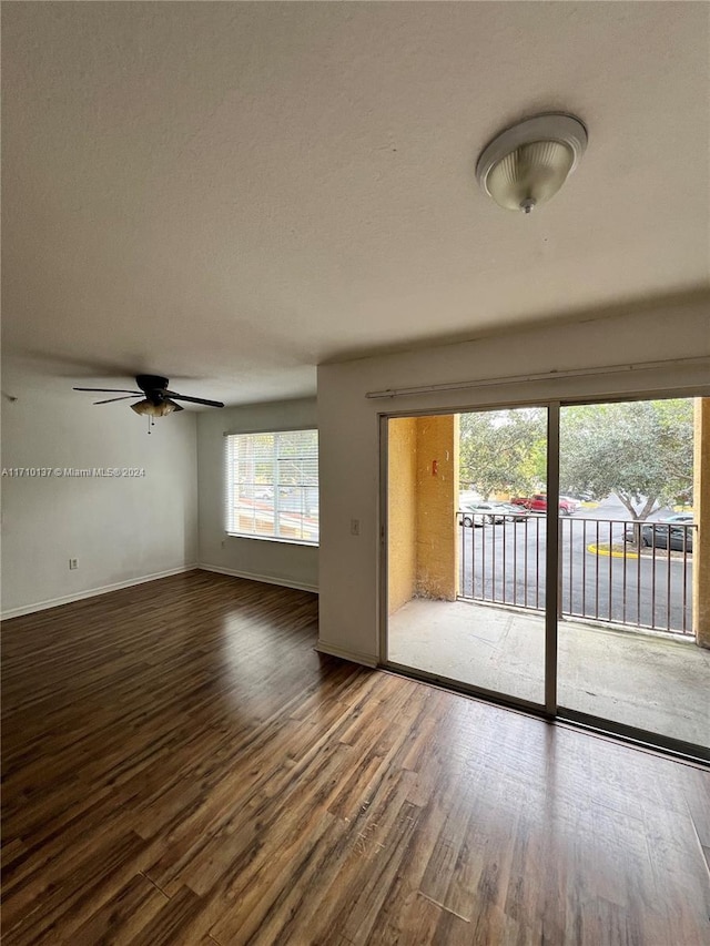 unfurnished living room with ceiling fan and dark wood-type flooring