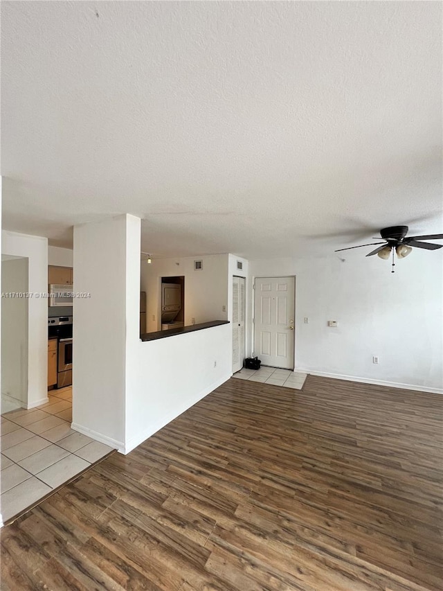 unfurnished living room featuring ceiling fan, light hardwood / wood-style floors, and a textured ceiling