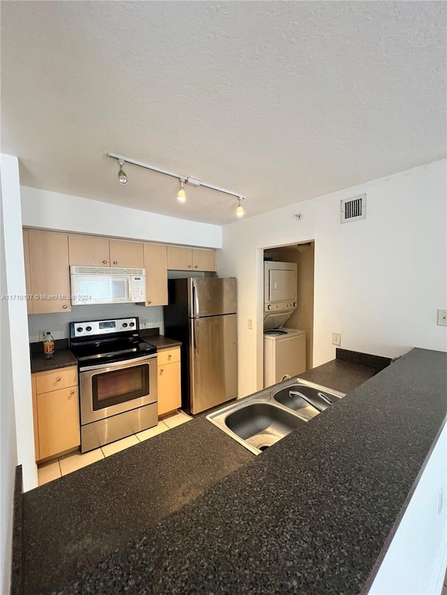 kitchen featuring sink, kitchen peninsula, stacked washer / dryer, and appliances with stainless steel finishes