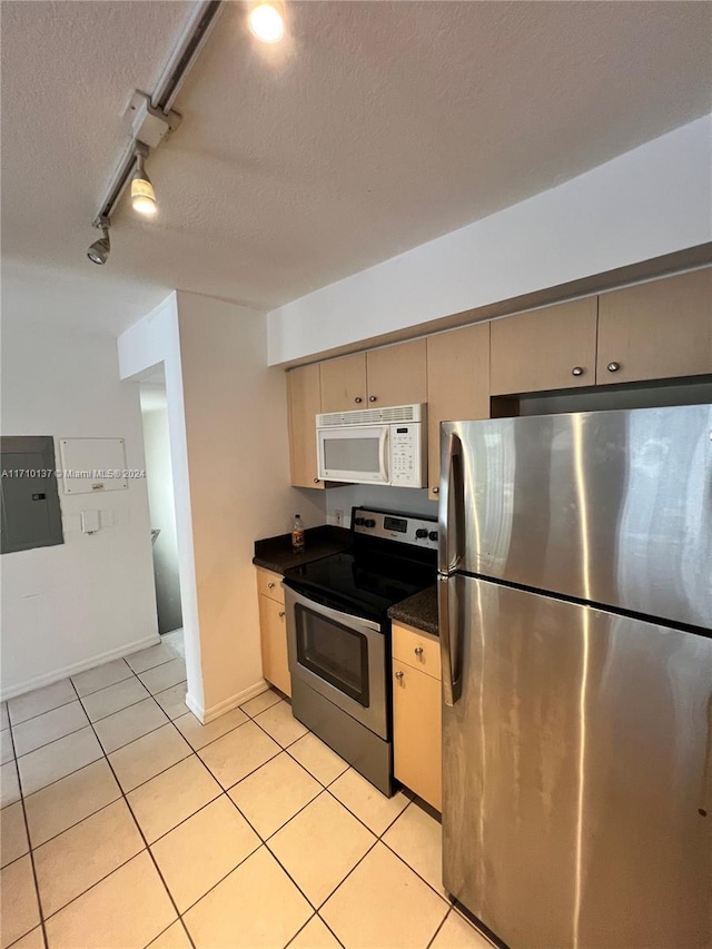 kitchen featuring a textured ceiling, rail lighting, stainless steel appliances, and light tile patterned flooring