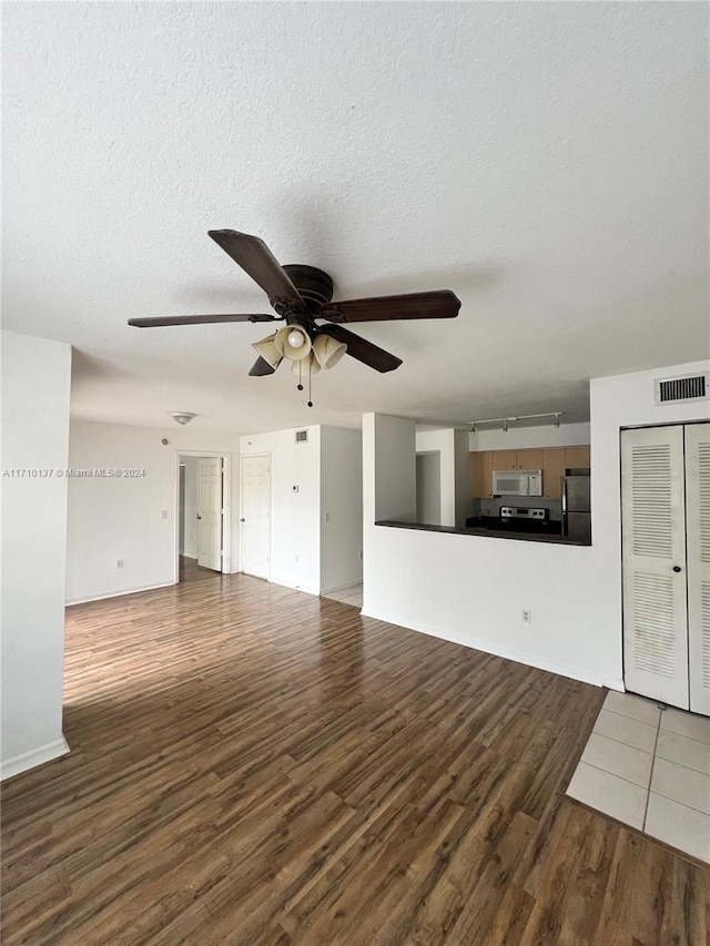 unfurnished living room with ceiling fan, dark hardwood / wood-style flooring, and a textured ceiling