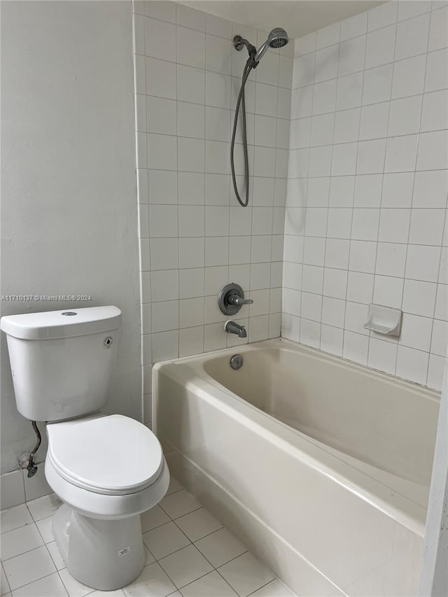 bathroom with tile patterned flooring, tiled shower / bath combo, and toilet