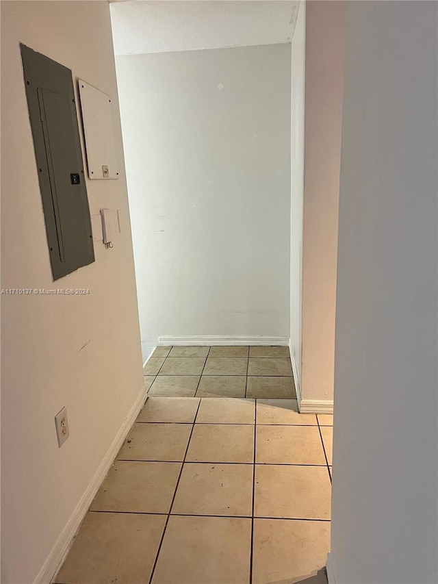 hall featuring light tile patterned flooring and electric panel