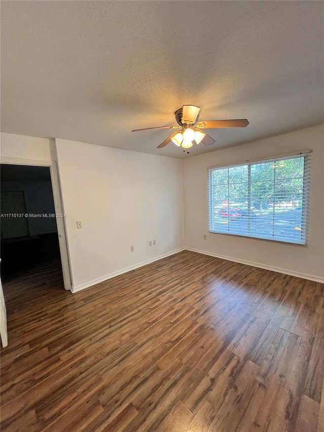 empty room with a textured ceiling, dark hardwood / wood-style floors, and ceiling fan