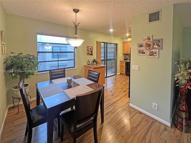 dining space with ceiling fan, a textured ceiling, and light hardwood / wood-style flooring