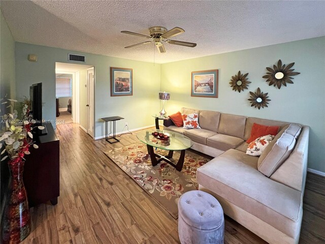 living room featuring ceiling fan, wood-type flooring, and a textured ceiling