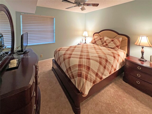 bedroom featuring carpet flooring, a textured ceiling, and ceiling fan