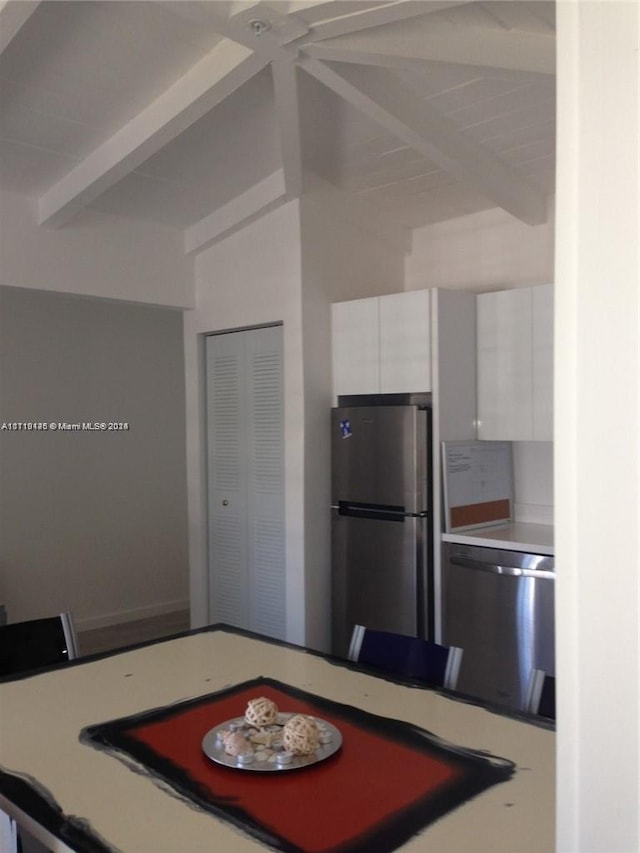 kitchen with beamed ceiling, stainless steel appliances, and white cabinetry