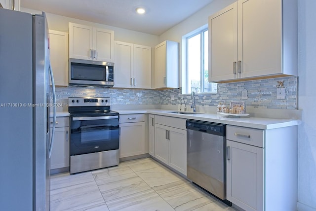 kitchen featuring backsplash, sink, white cabinets, and appliances with stainless steel finishes