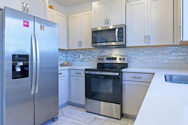 kitchen featuring decorative backsplash, appliances with stainless steel finishes, white cabinetry, and sink