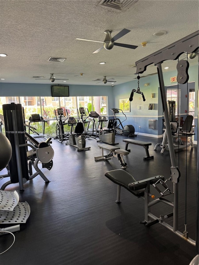 gym featuring ceiling fan, a healthy amount of sunlight, and a textured ceiling