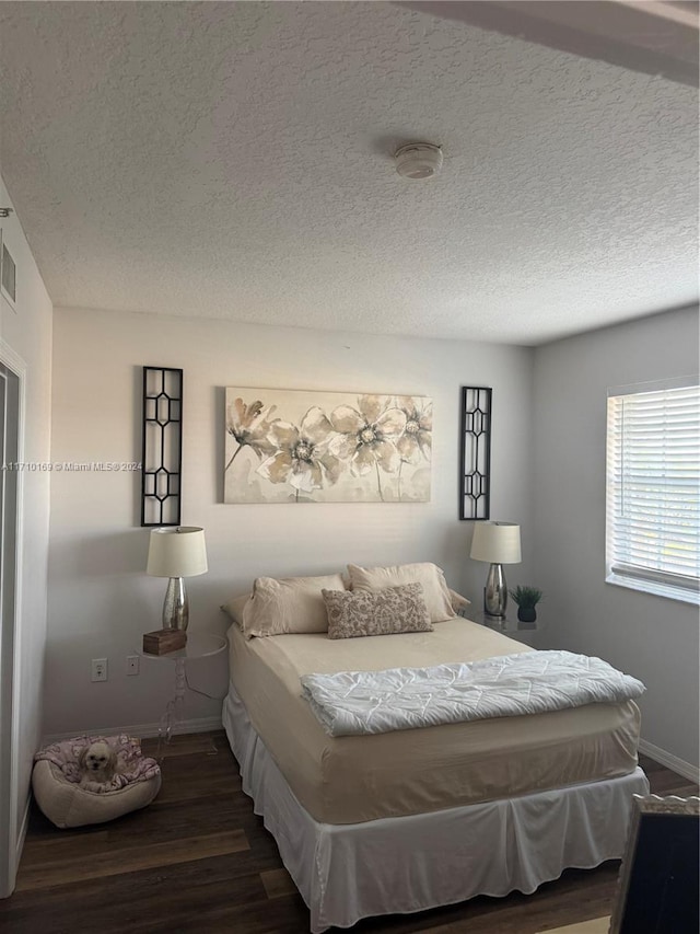 bedroom featuring dark hardwood / wood-style floors and a textured ceiling