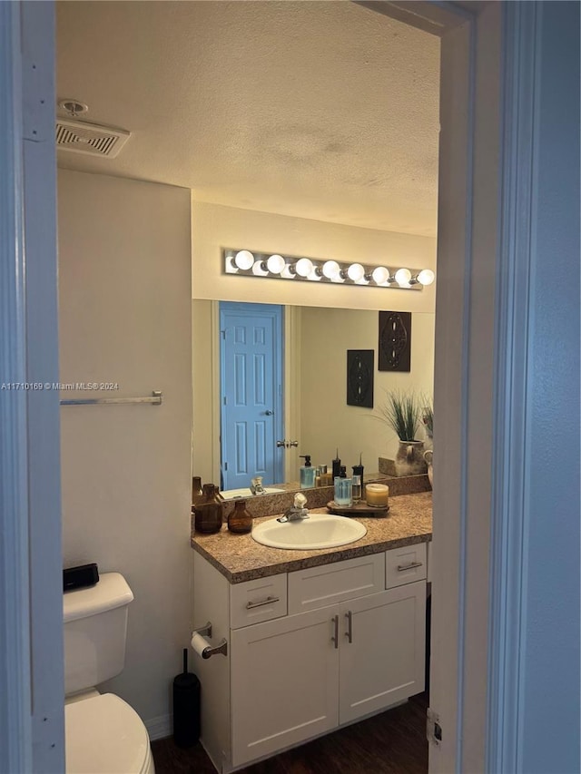 bathroom featuring vanity, toilet, wood-type flooring, and a textured ceiling