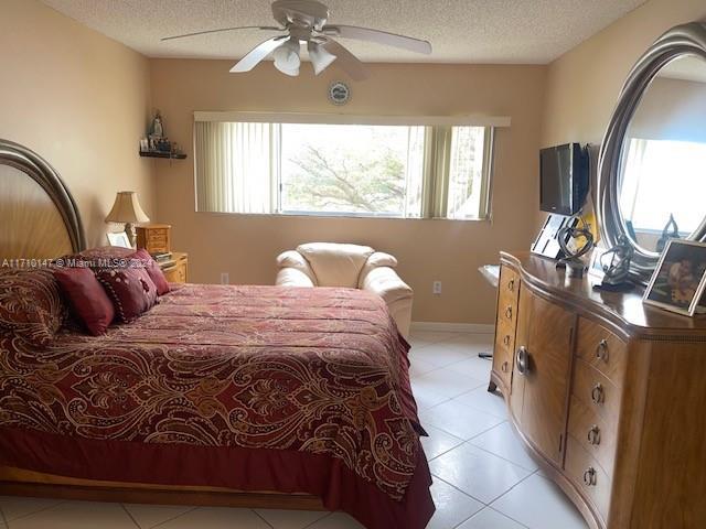 bedroom featuring light tile patterned floors, a textured ceiling, and ceiling fan