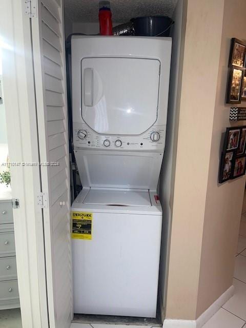 washroom featuring light tile patterned floors, a textured ceiling, and stacked washer / drying machine