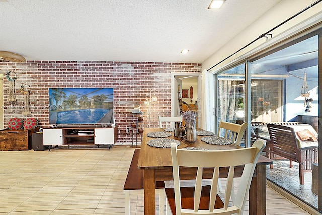 dining area featuring brick wall and a textured ceiling