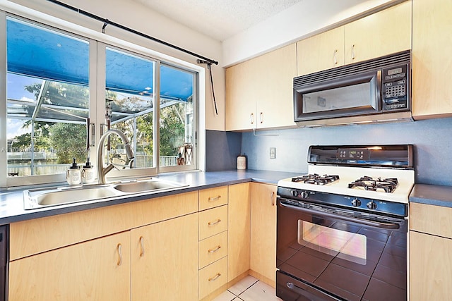 kitchen with gas stove, sink, a textured ceiling, and light brown cabinets