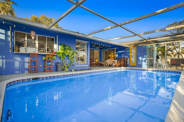 view of swimming pool featuring glass enclosure, ceiling fan, and a patio area