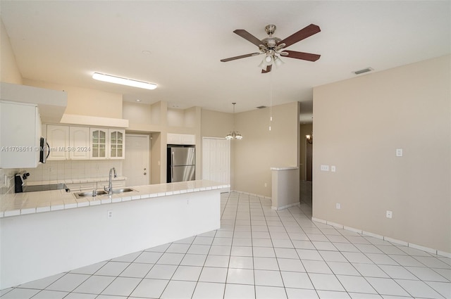 kitchen with kitchen peninsula, stainless steel appliances, sink, tile countertops, and white cabinetry