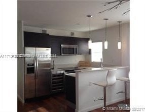 kitchen featuring kitchen peninsula, stainless steel appliances, dark wood-type flooring, sink, and pendant lighting