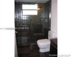 bathroom featuring tile patterned floors, vanity, toilet, and tiled shower