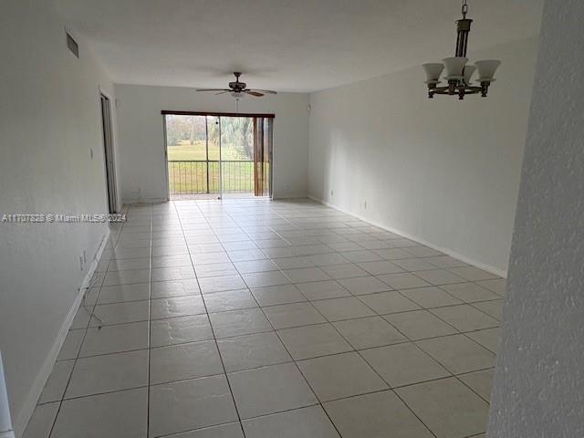 unfurnished room featuring ceiling fan with notable chandelier and light tile patterned floors