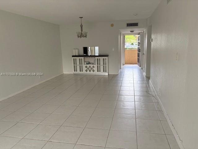 spare room featuring light tile patterned flooring and a chandelier