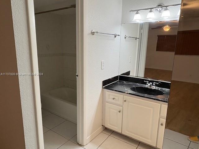 bathroom featuring tile patterned flooring, vanity, and washtub / shower combination