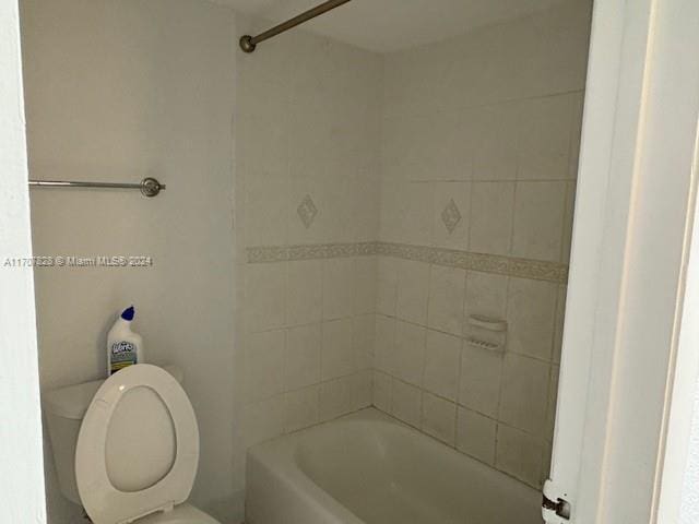 bathroom featuring toilet and tiled shower / bath