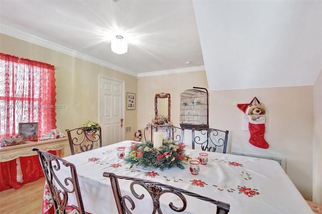 dining room with light wood-type flooring and crown molding