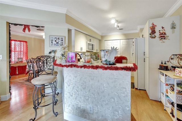 kitchen featuring white refrigerator, kitchen peninsula, light wood-type flooring, a breakfast bar, and ornamental molding