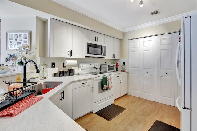 kitchen featuring light wood-type flooring, ornamental molding, white appliances, sink, and white cabinets