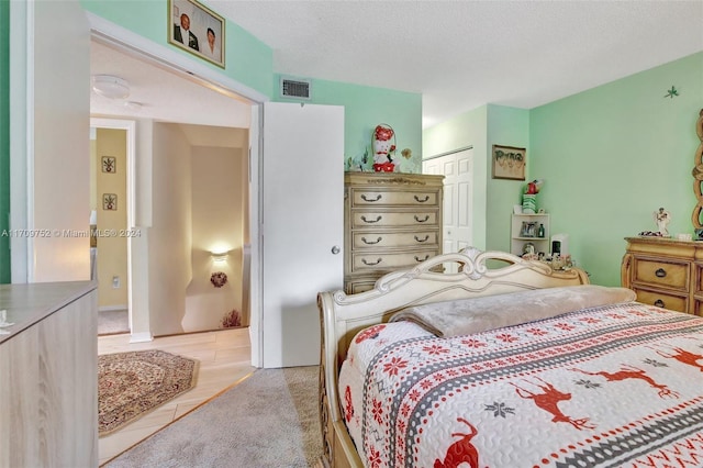 carpeted bedroom featuring a textured ceiling and a closet