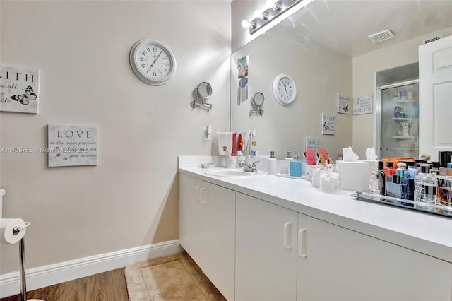 bathroom with wood-type flooring, vanity, and an enclosed shower