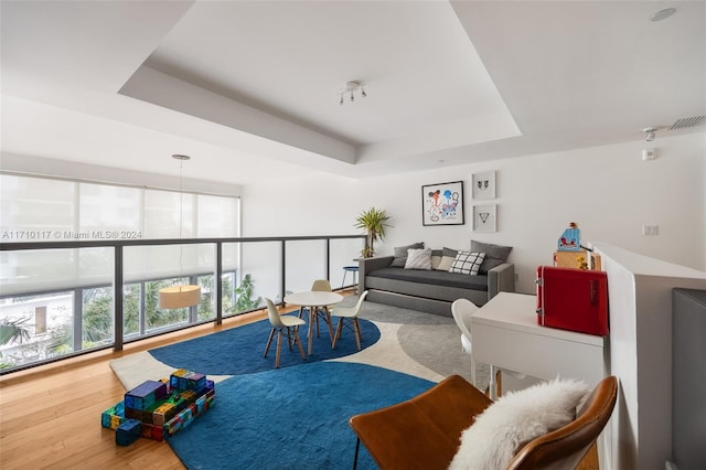 living room featuring a raised ceiling, hardwood / wood-style floors, and expansive windows