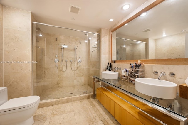 bathroom with vanity, a shower with door, toilet, and tile walls