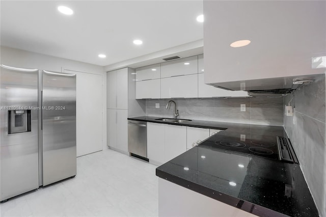 kitchen with exhaust hood, sink, decorative backsplash, white cabinetry, and stainless steel appliances