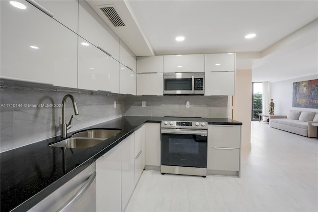 kitchen with white cabinets, appliances with stainless steel finishes, backsplash, and sink