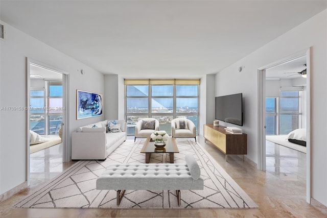 living room featuring ceiling fan and a wall of windows